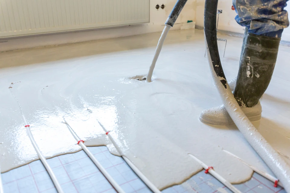 Ouvrier appliquant un revêtement de sol liquide autonivelant dans un intérieur résidentiel