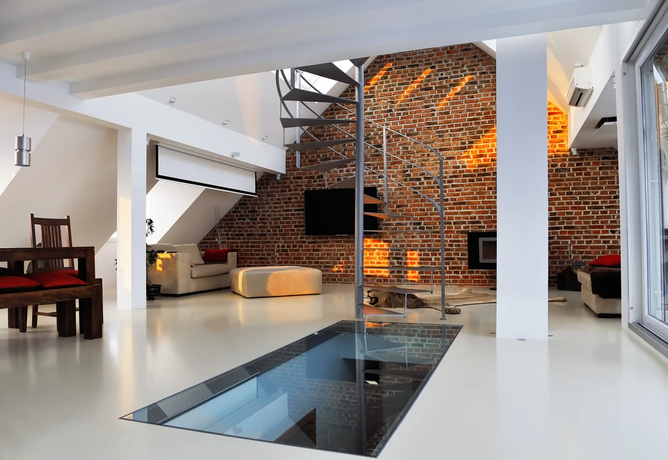 Intérieur résidentiel moderne avec escalier hélicoïdal métallique, mur en briques apparentes éclairé, sol en résine blanche brillante