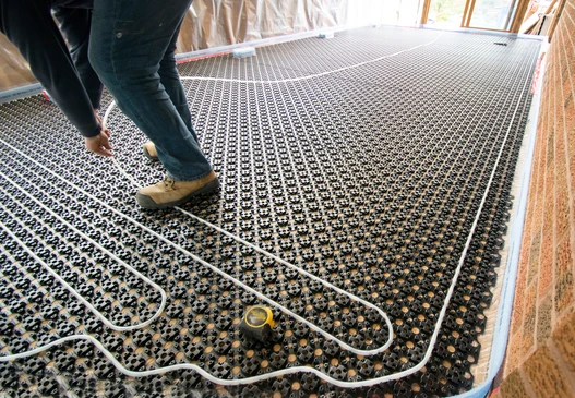 Photographie en gros plan d'un carreleur professionnel en &eacute;quipement de travail (gilet de s&eacute;curit&eacute;, bottes) appliquant du carrelage sur un mur ou un sol int&eacute;rieur. L'artisan doit tenir un outil de pose de carrelage (spatule crant&eacute;e, niveau, truelle) et on doit voir les carreaux partiellement pos&eacute;s sur la surface avec du mortier-colle. L'arri&egrave;re-plan doit montrer un environnement de chantier ou une zone r&eacute;nov&eacute;e avec les mat&eacute;riaux visibles. La composition doit mettre en &eacute;vidence le professionnalisme, la pr&eacute;cision de la pose et le travail de finition du carrelage, distinctement diff&eacute;rente d'une sc&egrave;ne de chape liquide.