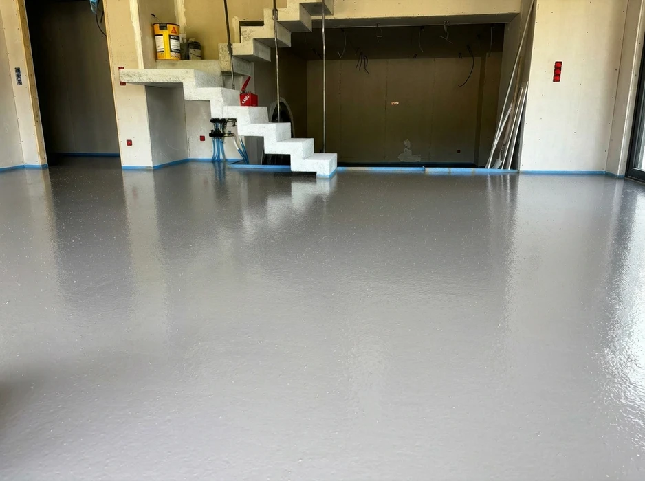 Photographie professionnelle en plongée d'une transition de revêtement de sol montrant plusieurs matériaux (chape grise polie, carrelage et parquet) juxtaposés sur un même sol, illustrant la complémentarité des solutions de PSEC. La perspective doit mettre en avant la variété des finitions et la qualité de la transition entre les matériaux, avec une lumière naturelle valorisant les textures et les teintes distinctes. Pas de personne, focus sur la technicité et la diversité des savoir-faire métier.