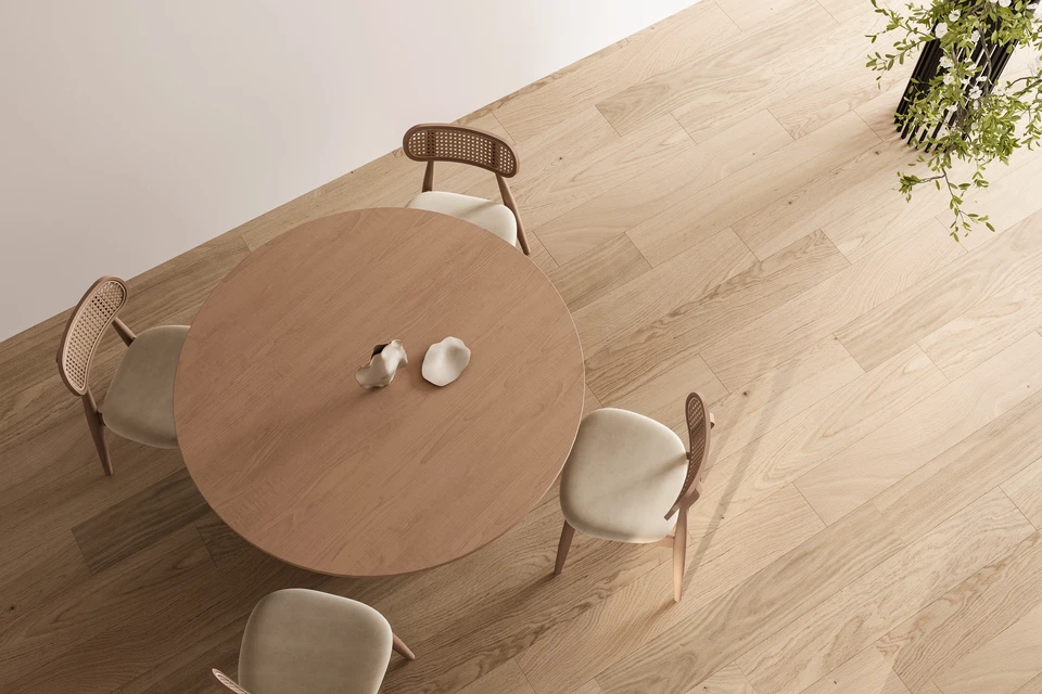 Photographie professionnelle d'un intérieur montrant un magnifique parquet en bois clair récemment posé dans un salon lumineux. Le parquet couvre entièrement le sol et brille légèrement sous la lumière naturelle entrant par une large fenêtre. La teinte miel chaleureux du bois et ses veines naturelles sont bien visibles. L'espace montre une pièce élégante et accueillante avec le parquet comme élément focal. La photo est prise en angle légèrement plongé pour bien mettre en valeur le revêtement de sol et sa qualité de pose régulière.