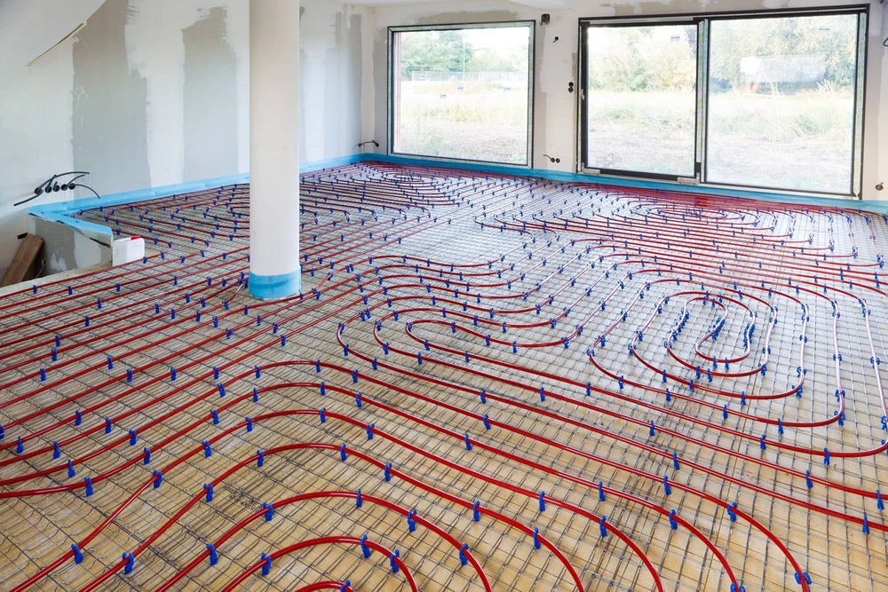 Technicien en combinaison de protection blanche intégrale applique de la mousse polyuréthane projetée sur le sol d'un chantier intérieur